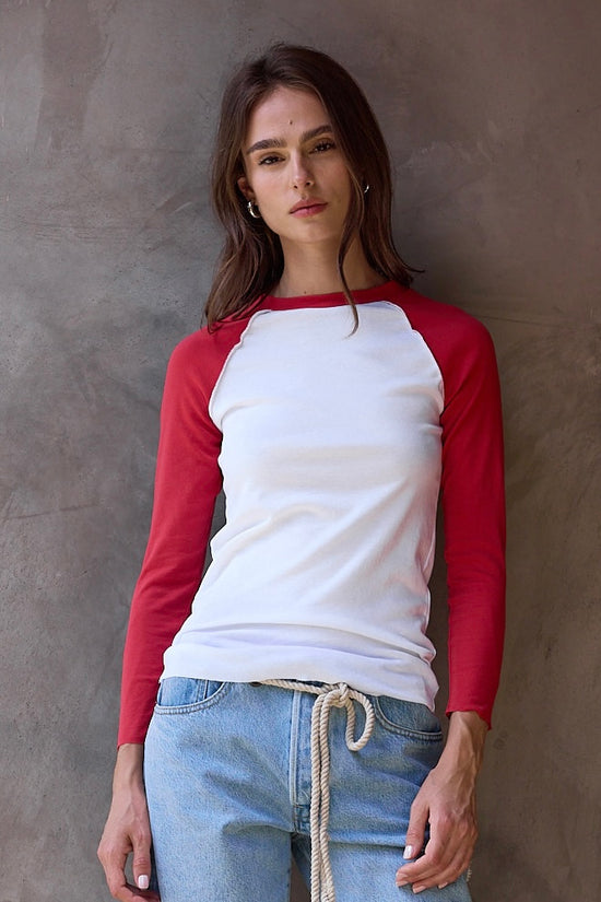 Woman wearing a red and white baseball shirt against a cement wall