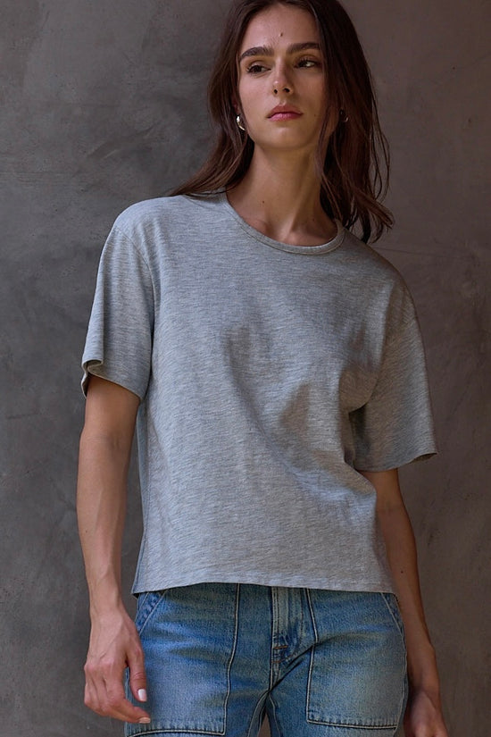Person wearing a gray t-shirt and blue jeans against a plain background