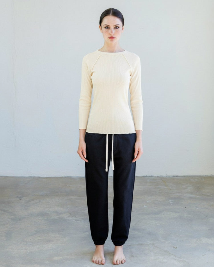 Model wearing Aria Rib Raglan Tee - Drift with black joggers in a minimalist setting.