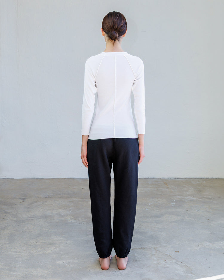 Aria Rib Raglan Tee- Pearl worn from the back with black pants showcasing its fitted design and bracelet-length sleeves.
