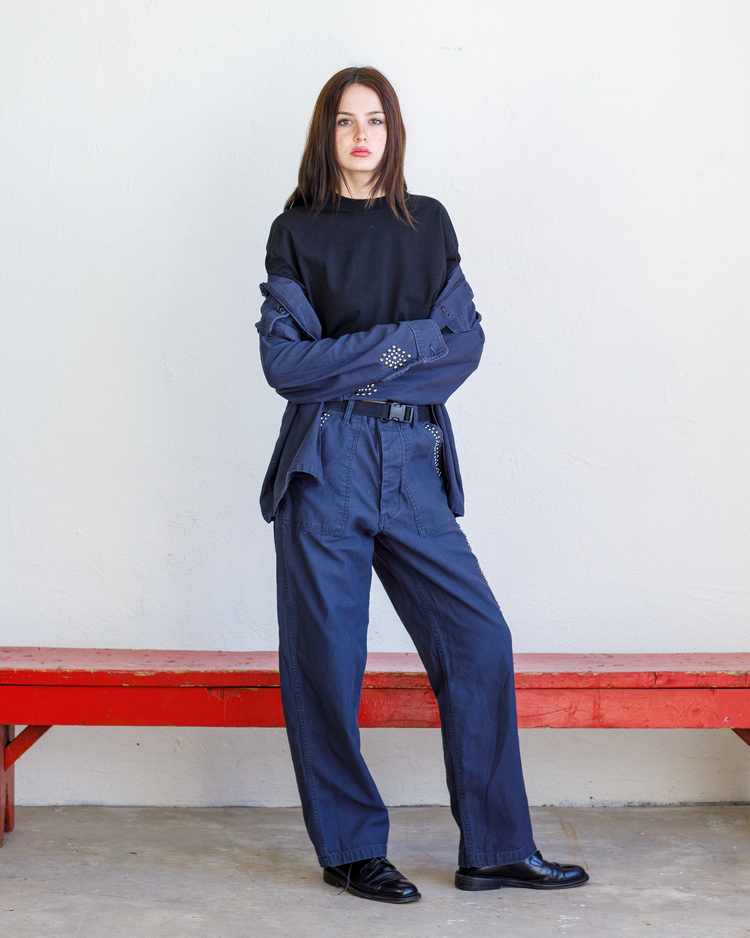 A woman wearing a studded navy Vintage military jacket and baker pant.