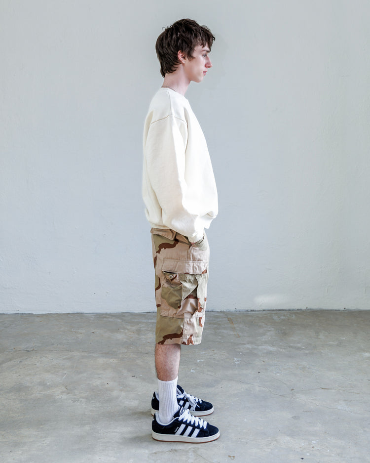 Jesse Twill Unisex Cargo Short - Desert worn by model, showcasing side view with white sweatshirt and black sneakers.