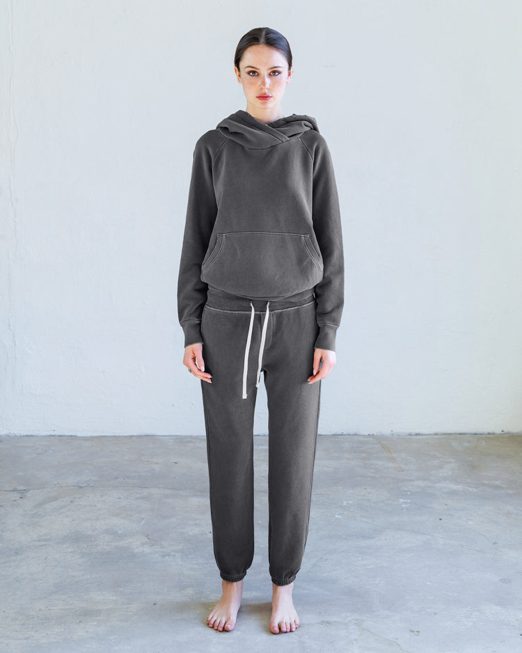 Lisse Loop Terry Hoodie - Aged Black displayed on model in a minimalist setting, showcasing its slim fit and oversized hood.