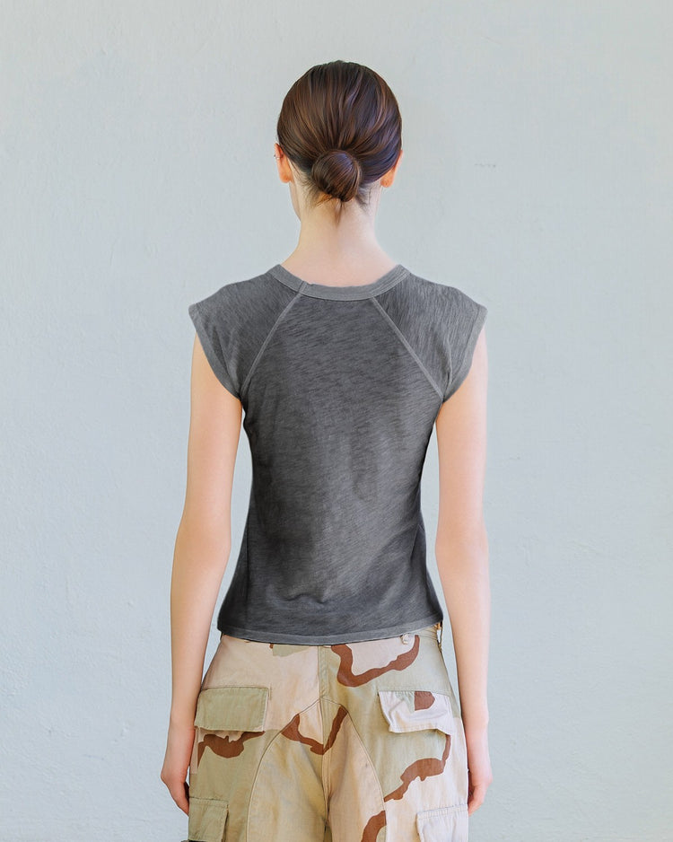 Person wearing a gray sleeveless top and camouflage shorts against a light gray background