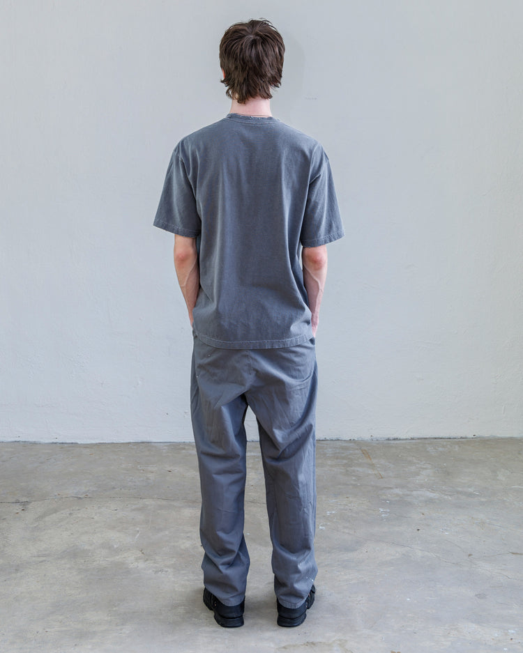 Model wearing the Turner Pleated Twill Unisex Trouser - Cement Workshop from the back, showcasing its relaxed fit.