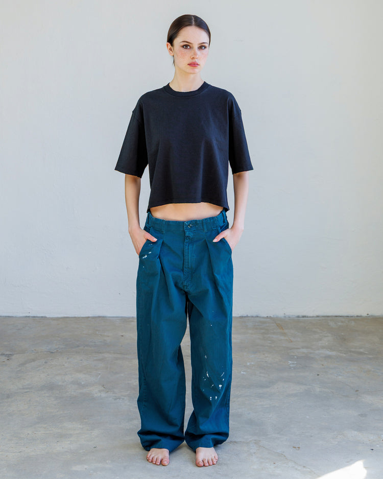 Model wearing Turner Pleated Twill Unisex Trouser - Teal Workshop, paired with a cropped black top.