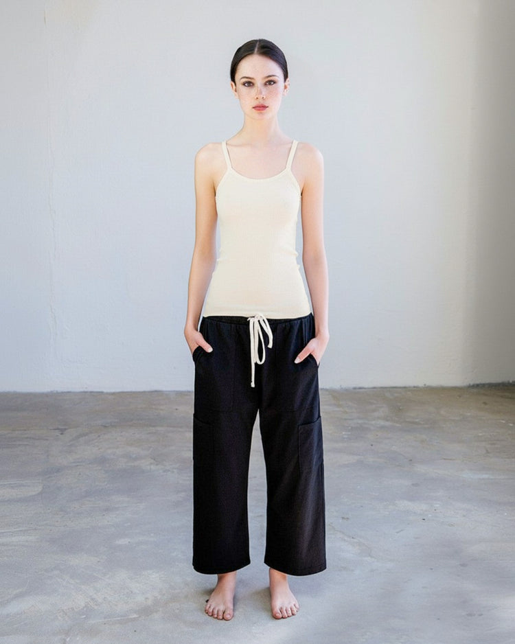 Model wearing the Kai Rib Cami Tank - Drift with black wide-leg pants in a minimalist setting.